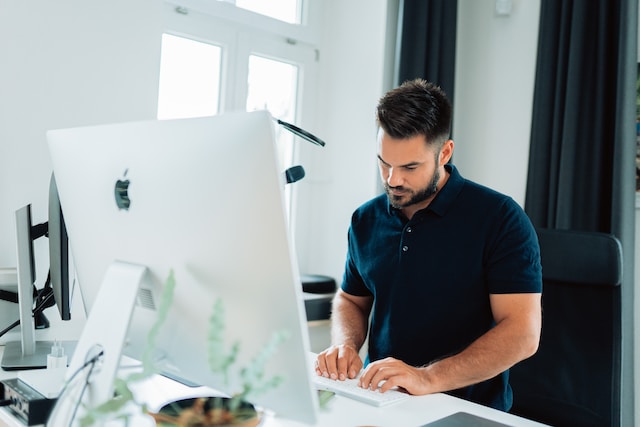 man typing on a mac computer